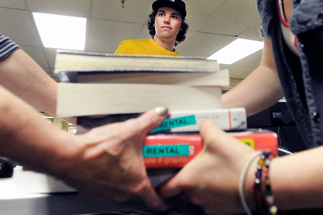 Evan Michalec, a sophomore from the University of Colorado, standing between people who carried his textbooks after selling them back to the CU bookstore.